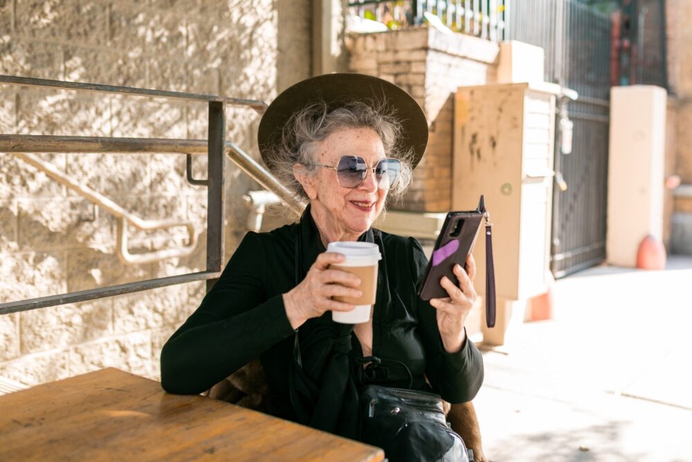 Бабушка на летнике пьет кофе во время прогулки
